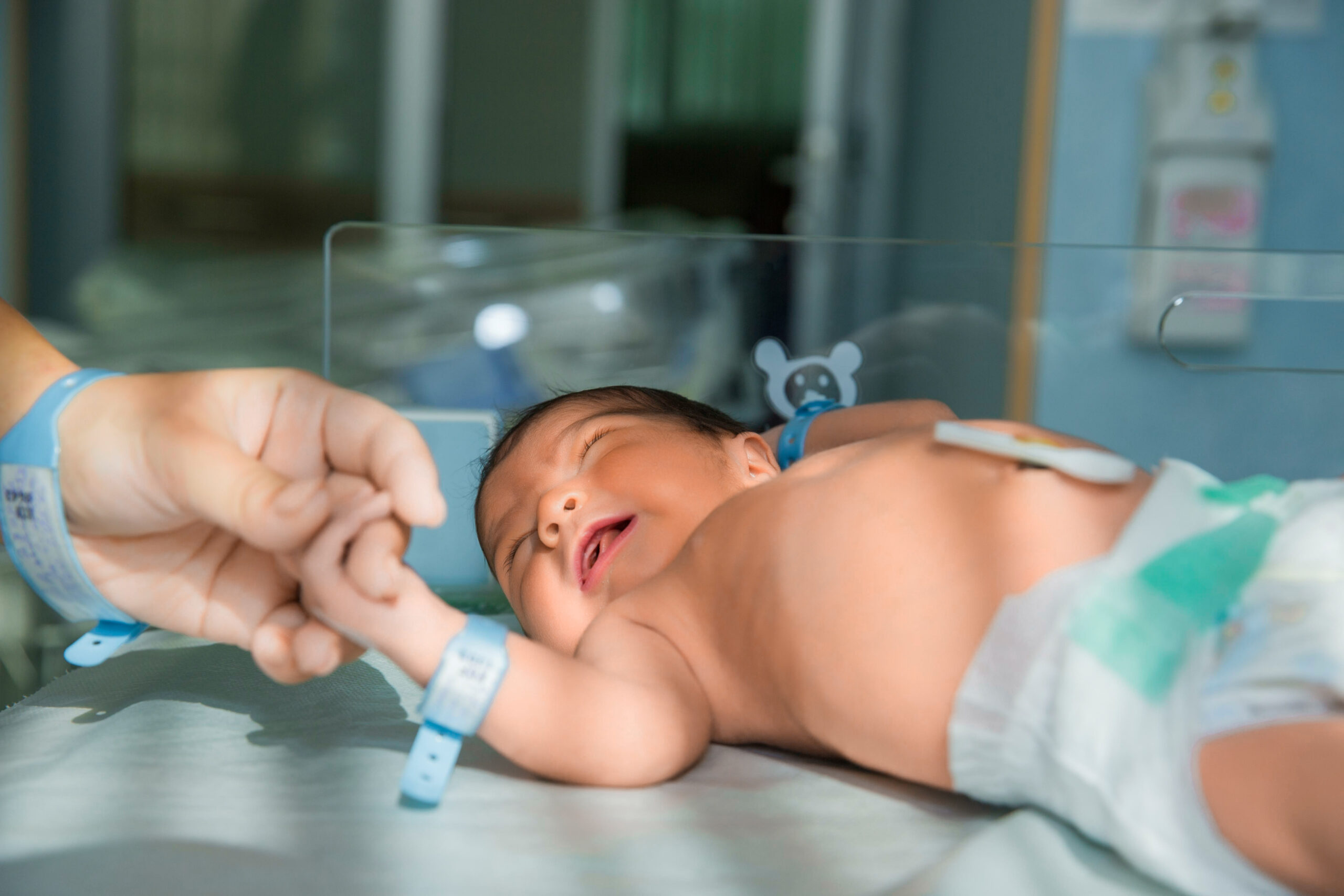 father holds hand of newly born babe in diapers